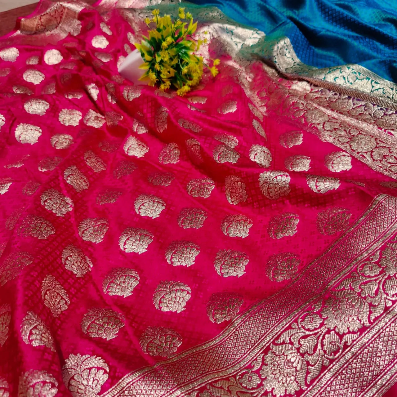 saree for women
A luxurious Banarasi silk saree displayed on a mannequin, featuring a rich combination of pink, blue, and gold tones. The saree is adorned with intricate gold zari weaving in traditional floral and geometric patterns, with a broad golden border adding elegance. The vibrant color gradient enhances its beauty, making it perfect for festive and wedding occasions.