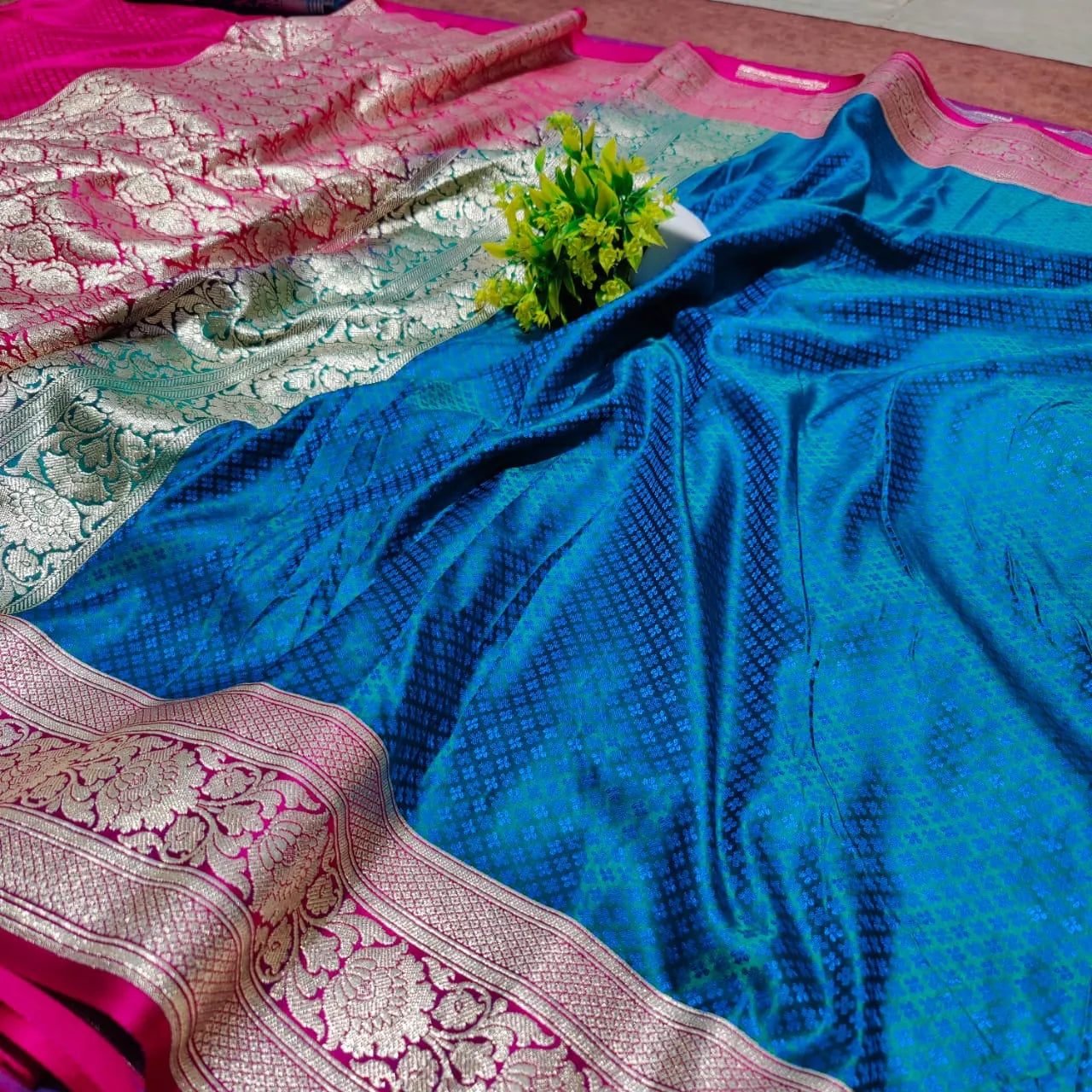 saree for women
A luxurious Banarasi silk saree displayed on a mannequin, featuring a rich combination of pink, blue, and gold tones. The saree is adorned with intricate gold zari weaving in traditional floral and geometric patterns, with a broad golden border adding elegance. The vibrant color gradient enhances its beauty, making it perfect for festive and wedding occasions.