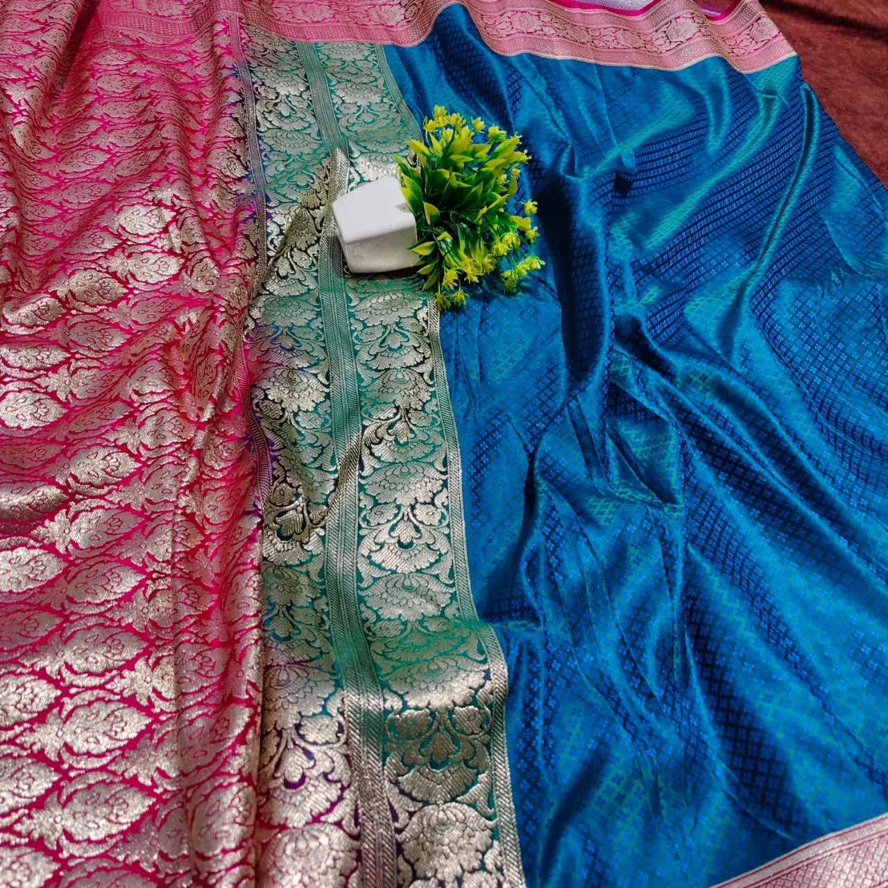 saree for women
A luxurious Banarasi silk saree displayed on a mannequin, featuring a rich combination of pink, blue, and gold tones. The saree is adorned with intricate gold zari weaving in traditional floral and geometric patterns, with a broad golden border adding elegance. The vibrant color gradient enhances its beauty, making it perfect for festive and wedding occasions.