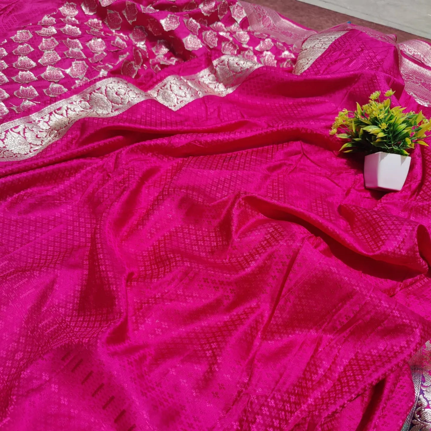 saree for women
A luxurious Banarasi silk saree displayed on a mannequin, featuring a rich combination of pink, blue, and gold tones. The saree is adorned with intricate gold zari weaving in traditional floral and geometric patterns, with a broad golden border adding elegance. The vibrant color gradient enhances its beauty, making it perfect for festive and wedding occasions.