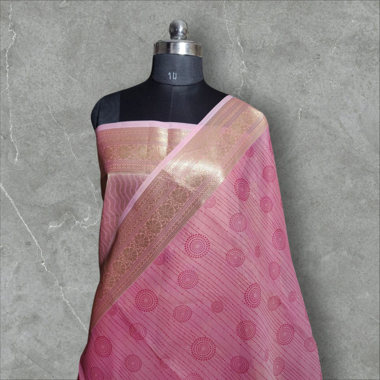 A beautiful organza silk saree in a soft pink color, featuring a lightweight, sheer texture with a subtle sheen. The saree drapes gracefully, adding an elegant and ethereal charm, perfect for weddings, festive occasions, and special events.