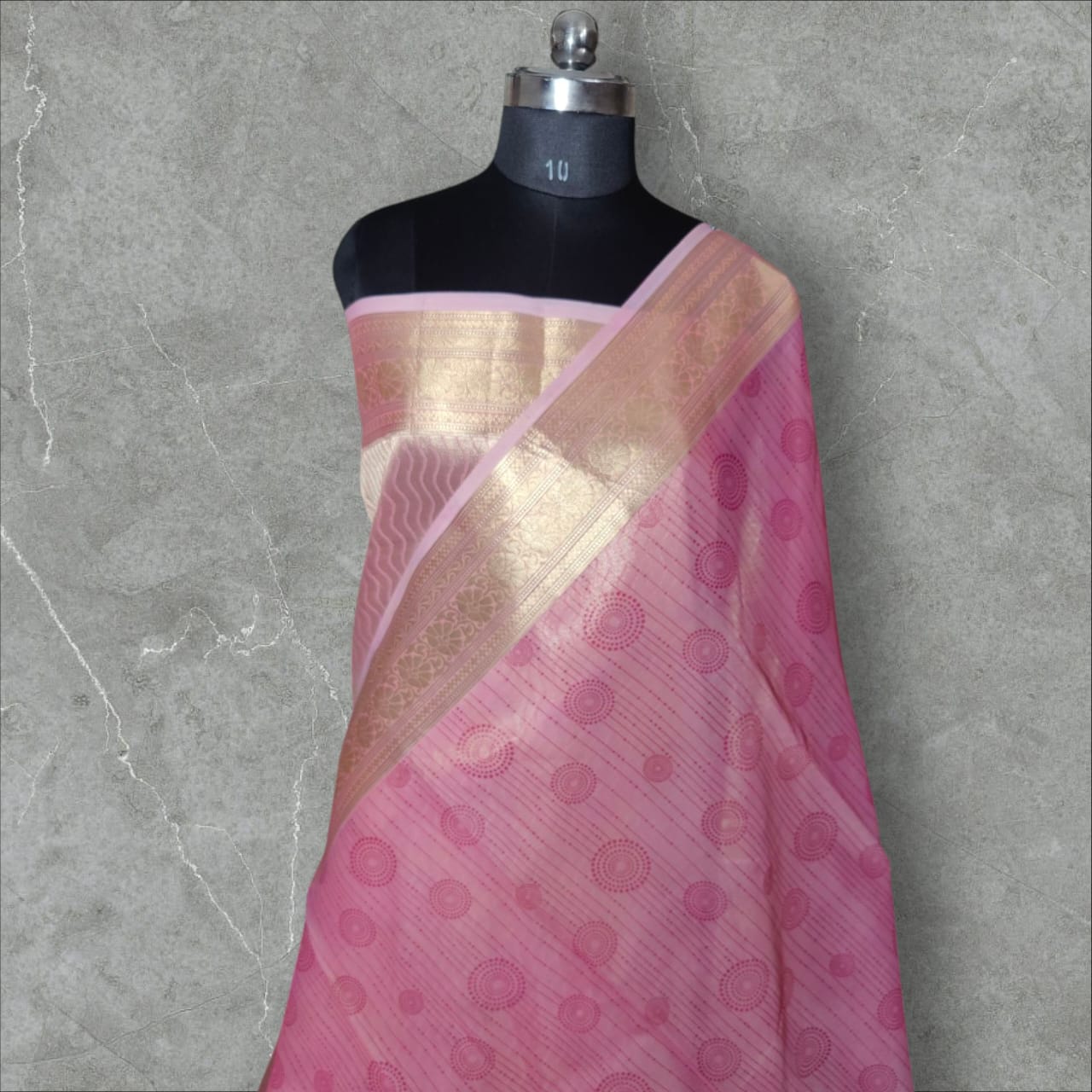 A beautiful organza silk saree in a soft pink color, featuring a lightweight, sheer texture with a subtle sheen. The saree drapes gracefully, adding an elegant and ethereal charm, perfect for weddings, festive occasions, and special events.