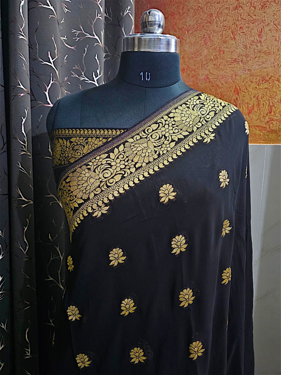 "Elegant black georgette saree with golden zari border and intricate pallu design"
